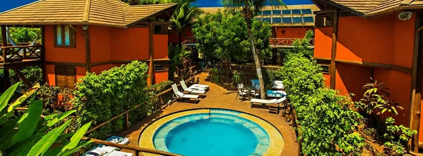 Piscina cercada por deck, guarda-corpos e estruturas de madeira na Pousada Triboju em Fernando de Noronha